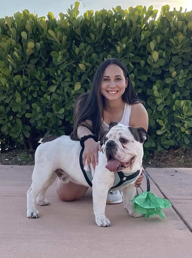 Melissa kneeling next to a white and brown bulldog