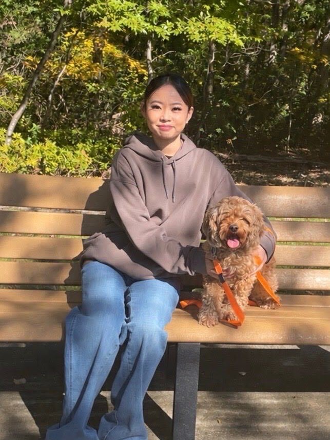 Michelle on a park bench with a small red poodle